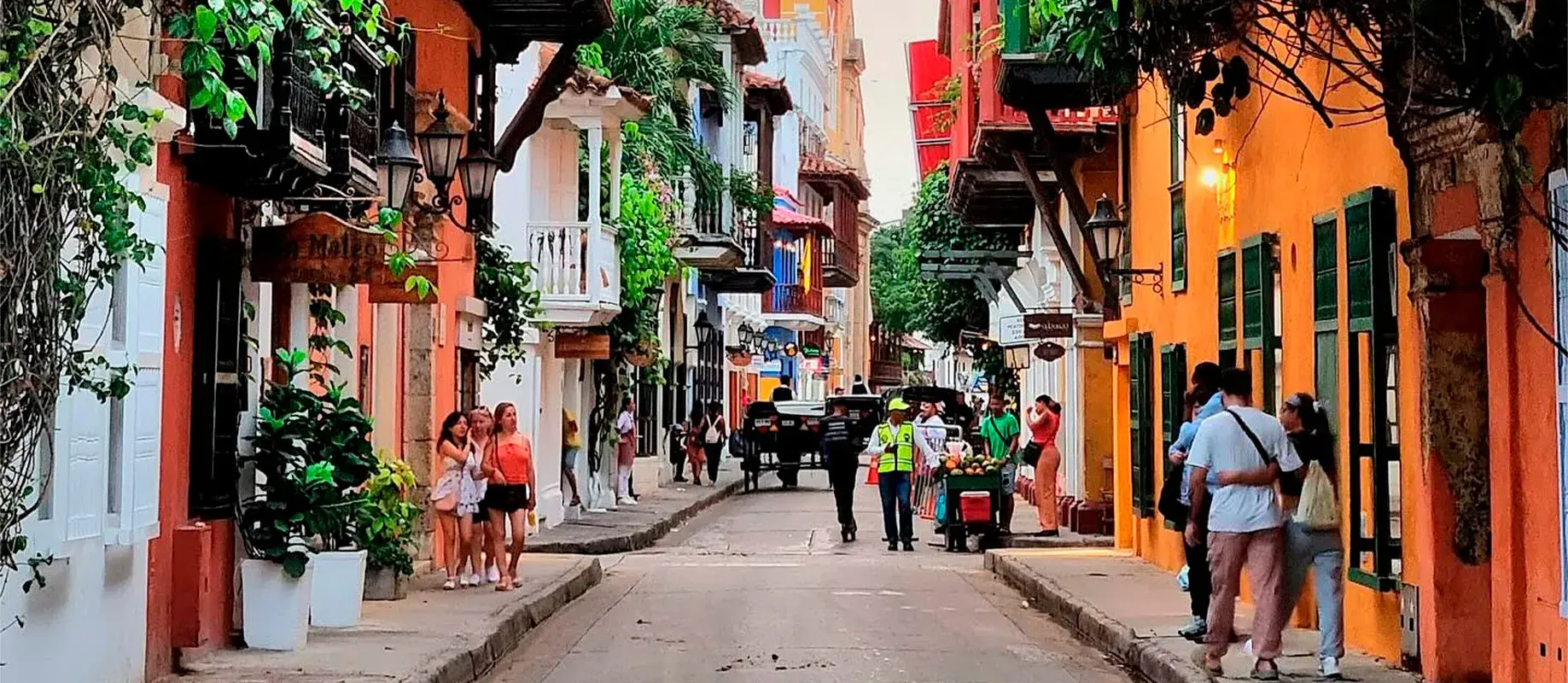 Calle colonial con balcones llenos de flores.